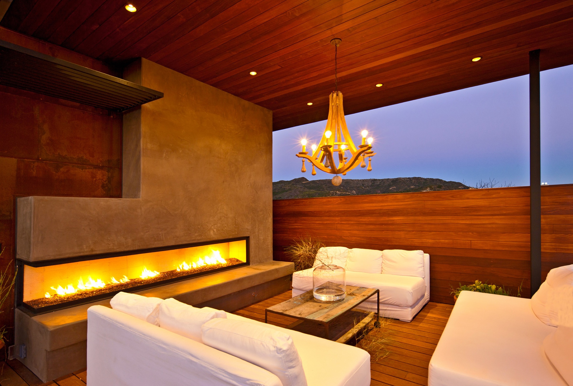 Indoor-outdoor living space with linear fireplace at dusk